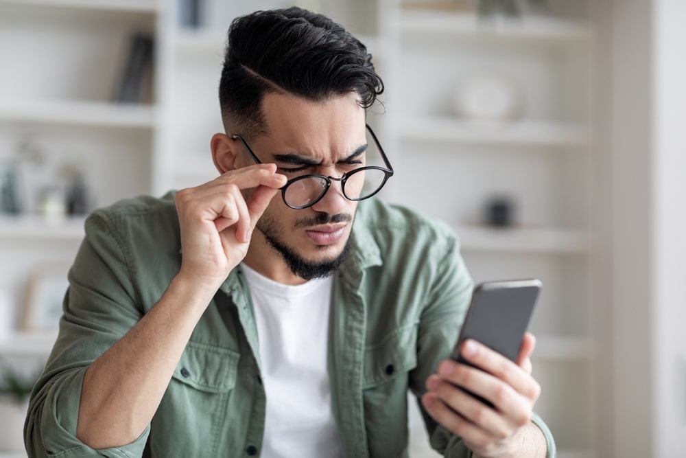 man struggling to see what is on his phone