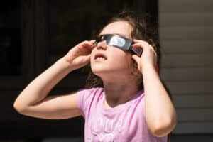 young girl viewing solar eclipse with eye protection