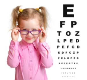 young girl putting on glasses prescribed to her by a childrens eye doctor